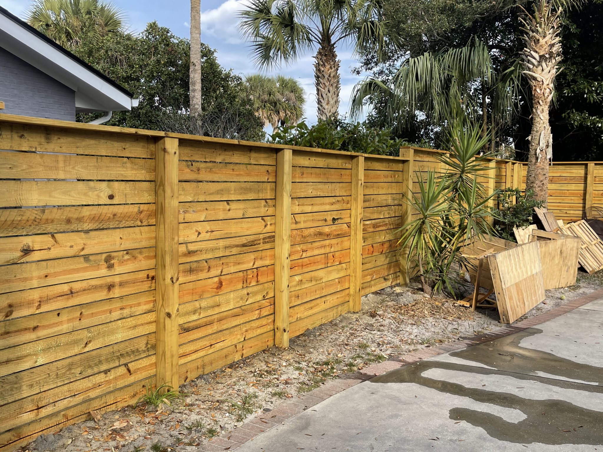 Horizontal cedar fence and palms behind a beach home