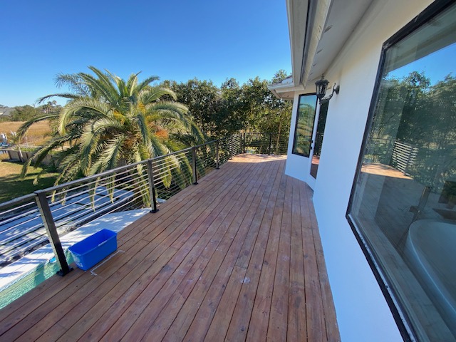 Hardwood deck with cable railing overlooking a pool