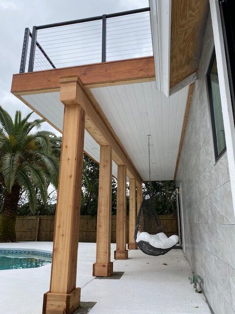 Row of cedar columns supporting a covered walkway beside a pool