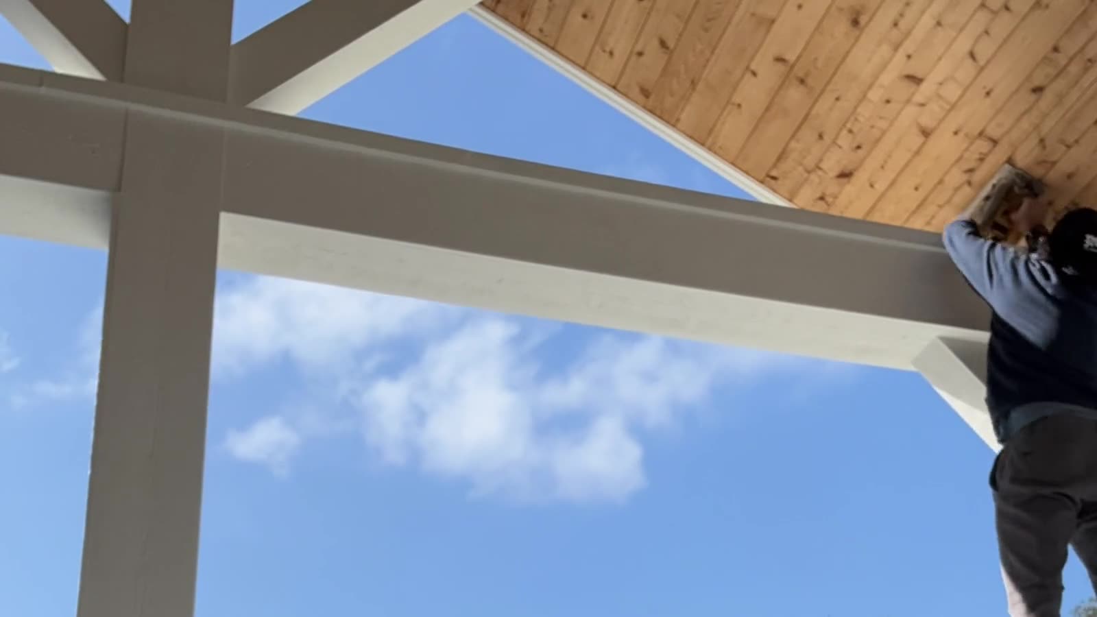 A carpenter fitting cedar tongue and groove into a covered pavilion ceiling at a Jacksonville beach home